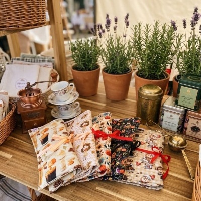 Mesa em madeira com vasos de plantas, tecidos coloridos, moedor de café, chávenas e latas metálicas