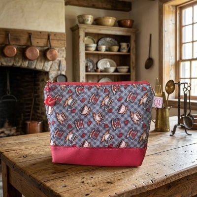 Bolsa com padrão de chávenas de chá, base vermelha, numa mesa de madeira rústica numa cozinha