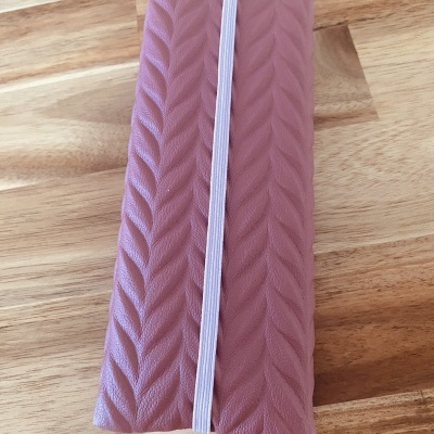 Carteira cor-de-rosa com padrão em trança e elástico branco