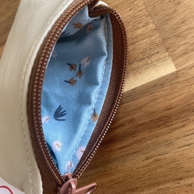 Porta-moedas bege com interior azul floral e fecho castanho