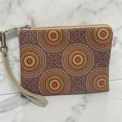 Bolsa de mão com padrão geográfico colorido, fecho bege e alça em pele clara