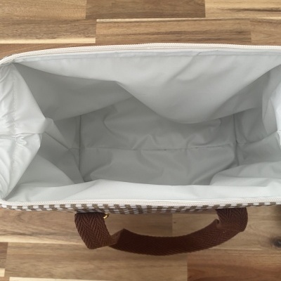 Bolsa térmica com interior branco e alças castanhas em padrão xadrez