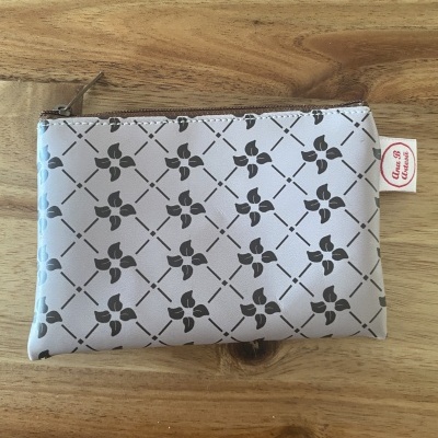 Carteira ou estojo em material branco com padrão de folhas pretas e fecho de zíper