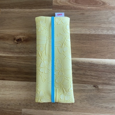 Estojo amarelo com padrão floral em relevo e elástico azul