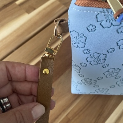 Mala azul claro com flores gravadas, fecho castanho e alça castanha com fecho dourado