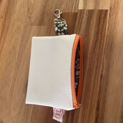Bolsa pequena branca em pele sintética com fecho laranja e alça floral com argola metálica
