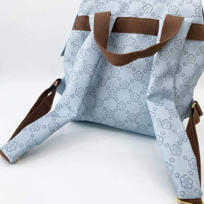 Mochila azul claro com flores azuis e alças castanhas