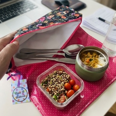 Estojo floral aberto com talheres e comida num local de trabalho