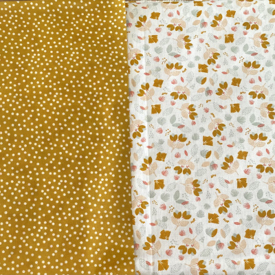 Tecido amarelo mostarda com bolinhas brancas e tecido branco com estampa floral colorida.