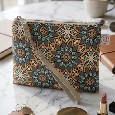 Bolsa de mão colorida com padrão floral, chave, batom, estojo e chávena num fundo de mesa de mármore.