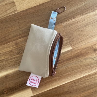 Mini bolsa bege com fecho de correr castanho e asa azul clara com padrão floral
