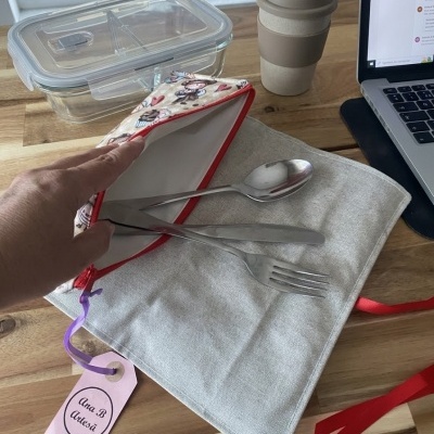 Talheres em bolsa estampada, frasco reutilizável, caixa plástica transparente, computador portátil num ambiente de trabalho