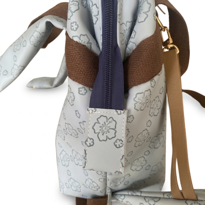 Bolsa com padrão floral cinza claro e alças castanhas.