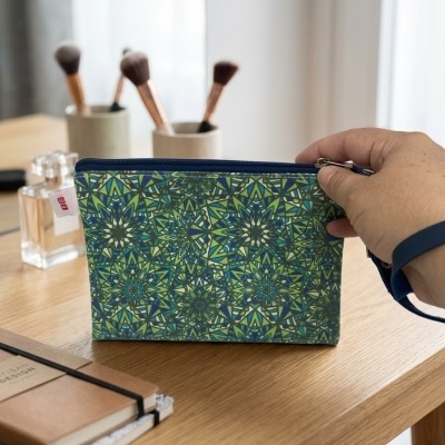 Bolsa para cosméticos com padrão geométrico colorido em mesa com pincéis e perfume
