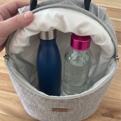 Bolsa térmica cinzenta com duas garrafas, uma azul metálica e outra de plástico transparente com tampa rosa