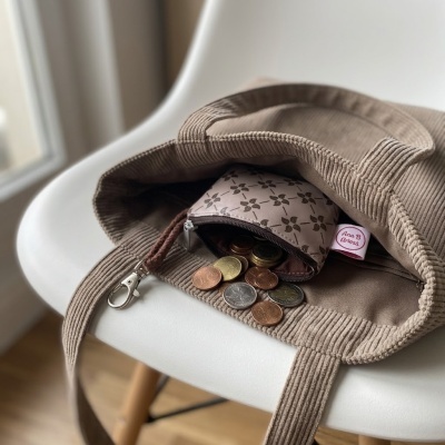 Bolsa castanho claro com carteira de moedas sobre cadeira branca