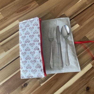 Talheres em estojo tecido com bolsa estampada sobre mesa de madeira