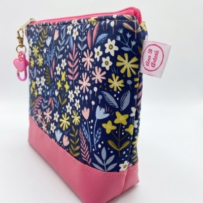 Bolsa com padrão floral colorido e base rosa com fecho rosa e pendente de coração