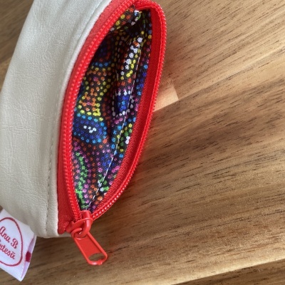 Bolsa pequena branca com fecho vermelho e interior colorido
