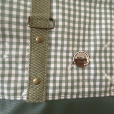 Bolsa com padrão xadrez verde e branco e alça verde com fivelas metálicas
