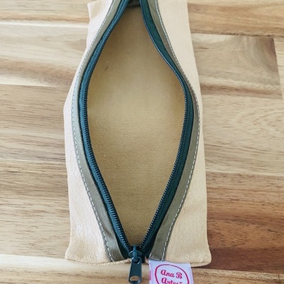 Estojo bege com fecho zip verde e etiqueta Ana B Artesã