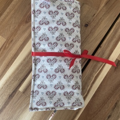 Estojo de tecido com padrão floral e fita vermelha sobre mesa de madeira