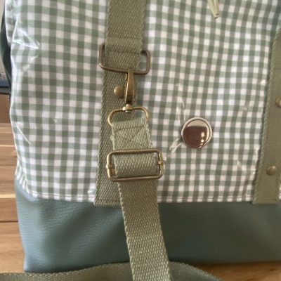 Mochila verde e branca com padrão aos quadrados e fivela metálica