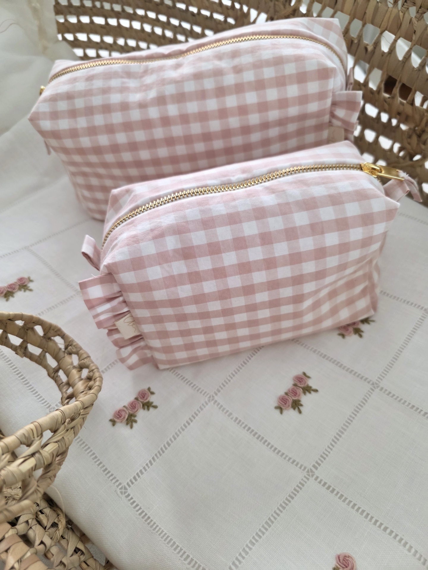saquinho necessaire Bolsas de tecido xadrez rosa e branco com fechos dourados sobre toalha branca bordada