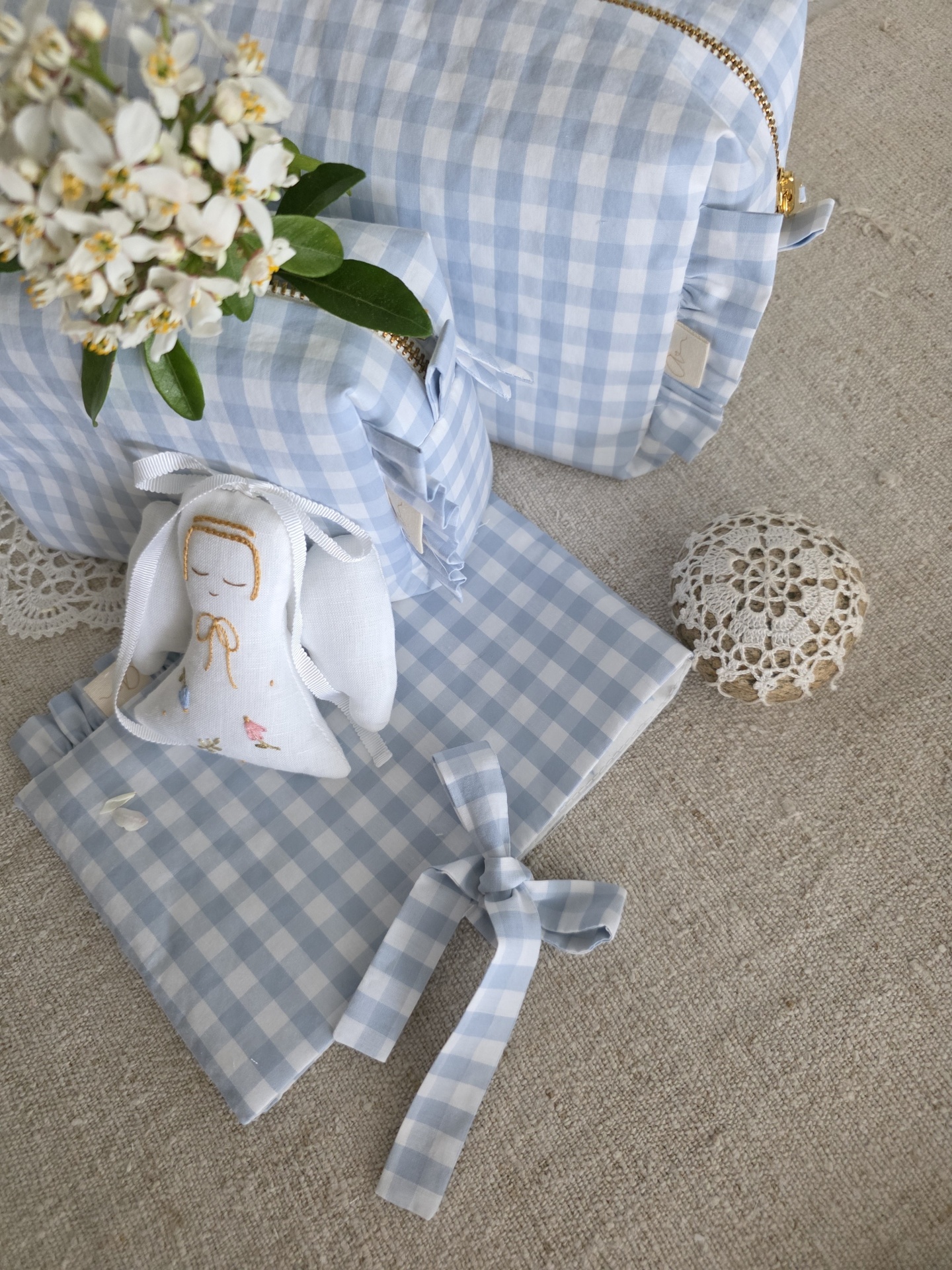 saquinho necessaire Acessórios em xadrez azul claro e branco com necessaire, saco, laço e bolsa, flor branca e peça rendada