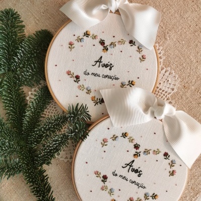 Aros de bordado redondos com tecido branco, bordados florais coloridos e texto 