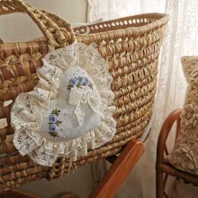 Berço de vime com pendente de coração em tecido com renda e bordado azul