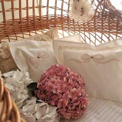 Cadeira de vime com almofadas bordadas, flores artificiais, e coração decorativo pendurado