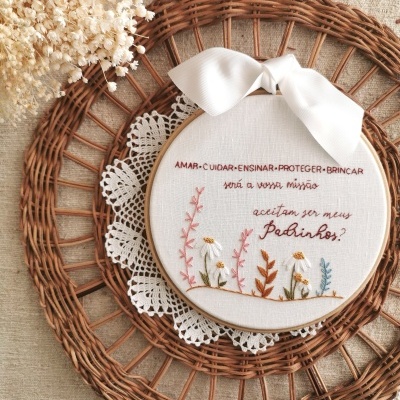 Aro de bordado com mensagem bordada e flores em tecido branco, fita branca e aro de vime redondo