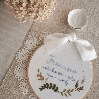 Anel bordado com nome e dados de nascimento, flores secas e prato branco com coração