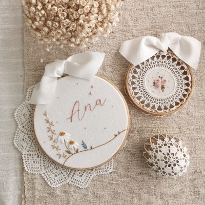 Três peças bordadas decorativas com fitas e renda sobre tecido bege