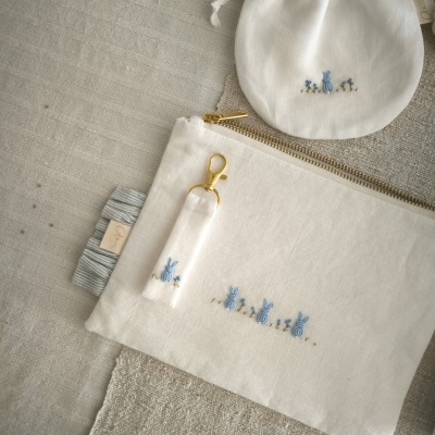 Conjunto de saco branco com fecho e saco de pano bordados com coelhinhos azuis