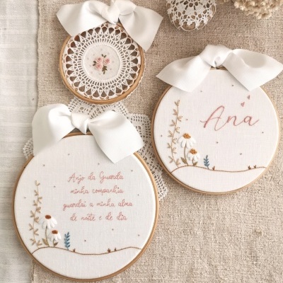 Bordados em bastidores de madeira com laços brancos e flores em tecido bege