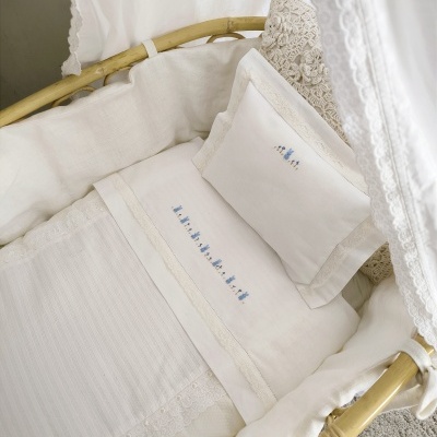 Berço de vime com roupa de cama branca e cortinas rendadas