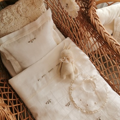 Berço de vime com roupa de bebé branca bordada