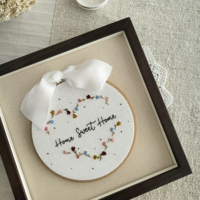 Bordado decorativo com flores e texto em moldura de madeira