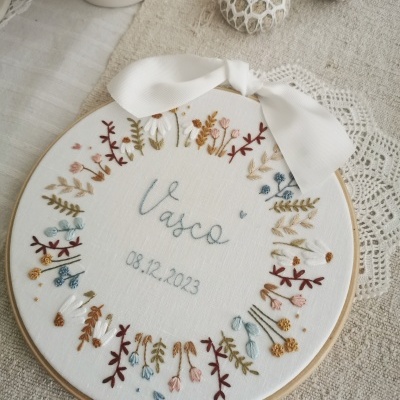 Bordado circular em madeira com flores coloridas e nome Vasco com data