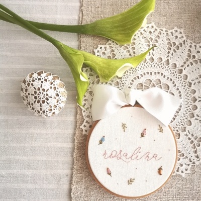 Bordado redondo com fita branca e o nome 