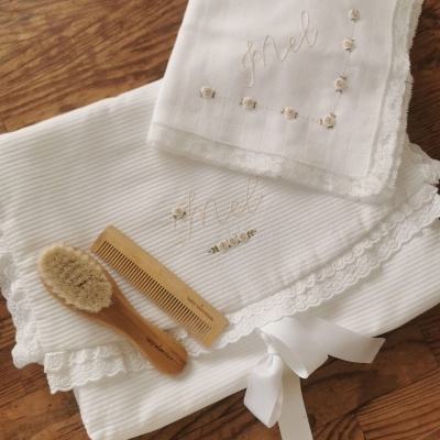 Conjunto branco com bordados, escova e pente em madeira sobre mesa de madeira
