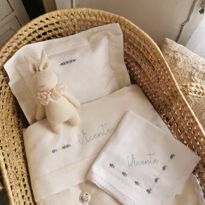 Berço de verga com roupa de cama branca bordada e brinquedo de peluche coelho em croché creme