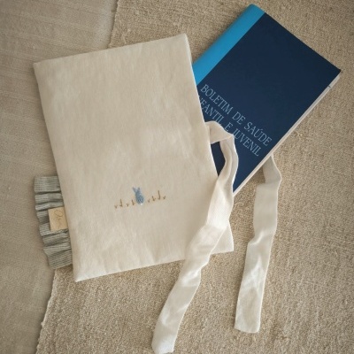 Capa de tecido branco com bordado e livro azul