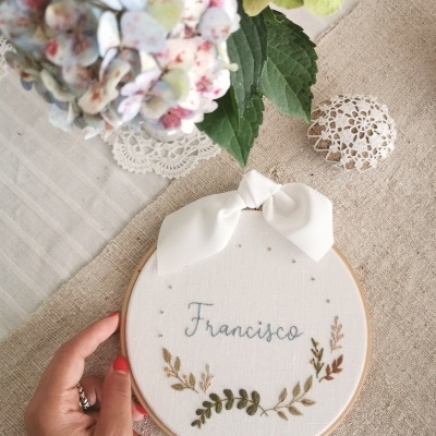 Moldura redonda de bordado com o nome Francisco e folhagem bordada em tecido branco