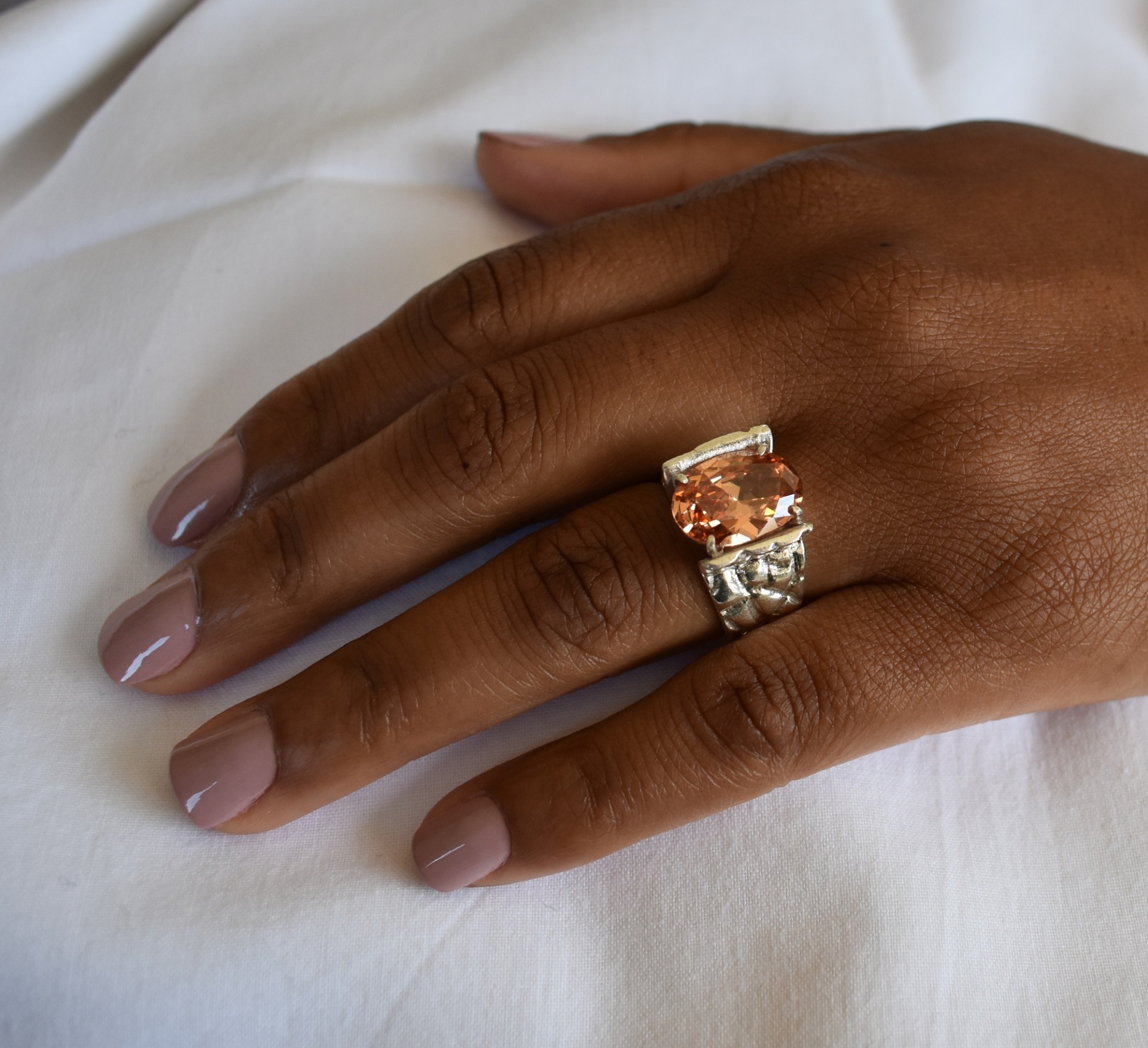 Anel Ladeira Anel com pedra cor de pêssego em mão feminina com unhas pintadas rosa claro