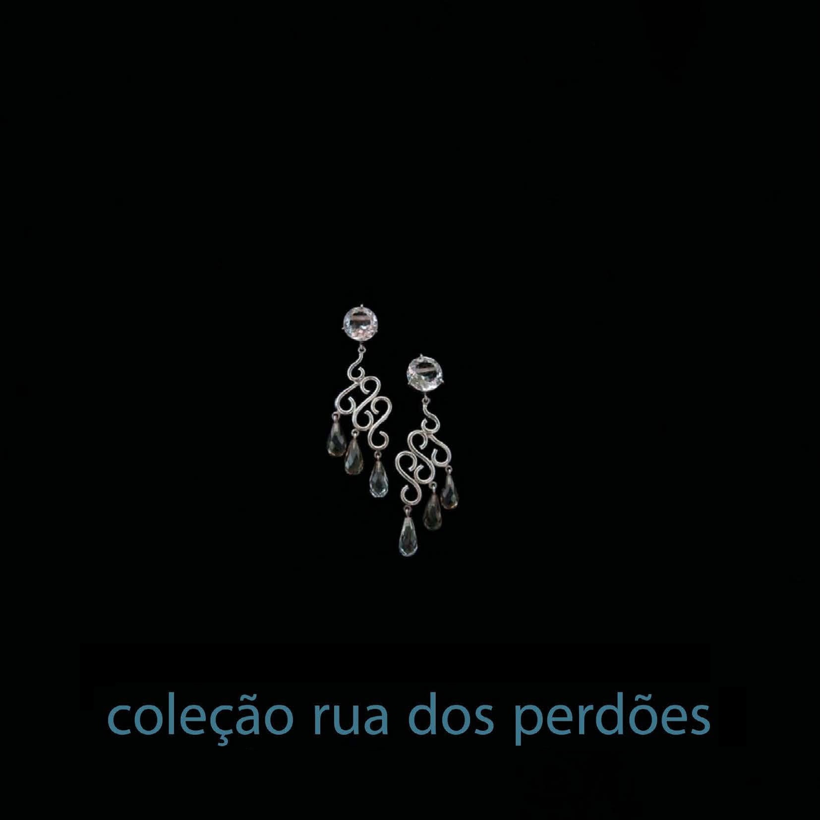 Brincos Rua dos Perdões Brincos pendentes prateados com pedras transparentes em fundo preto