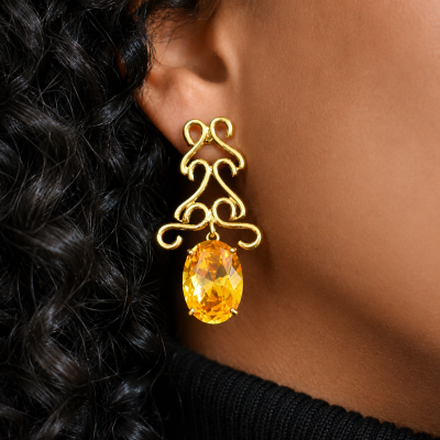 Brinco dourado com pedra âmbar e cabelo encaracolado preto