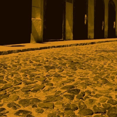 Calçamento de pedras irregulares com edifícios e sombras fortes
